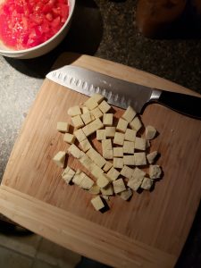 raw paneer cut into cubes on cutting board