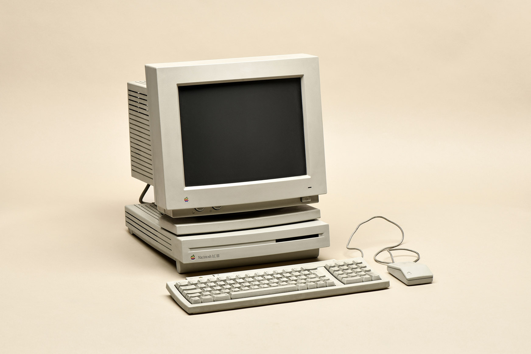 Macintosh LC III from 1994. Retro personal computer manufactured by Apple Computer Inc. with monitor, keyboard and mouse, isolated on beige background